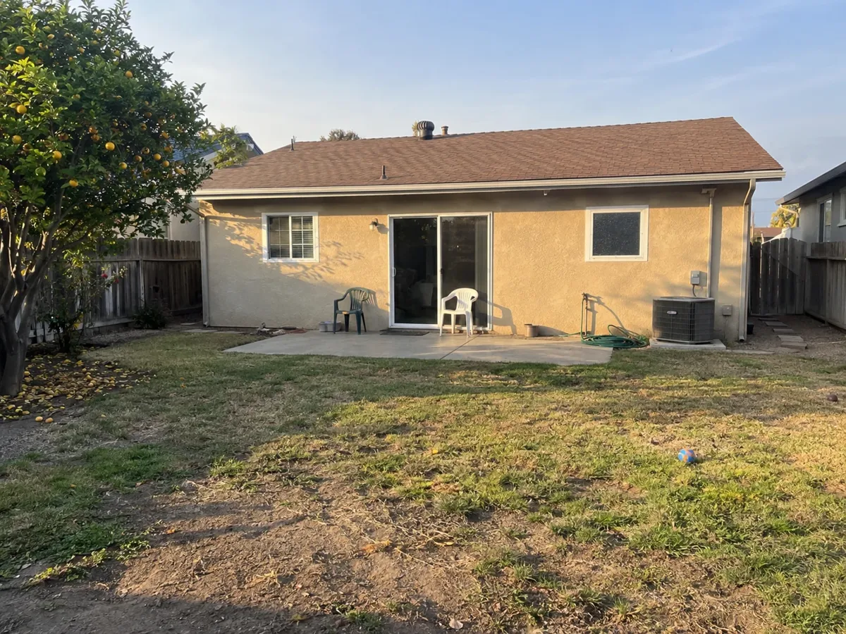 The backyard today: patchy lawn, cracked slab and plastic chairs